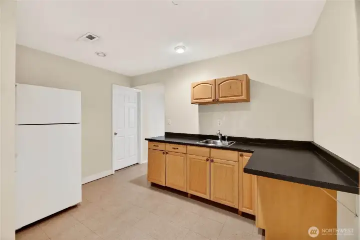 KITCHENETTE  Single sink / Laminate counter / Upper and lower cabinets  Refrigerator/freezer  Door to rear yard with motion sensor light  Location of utility panel