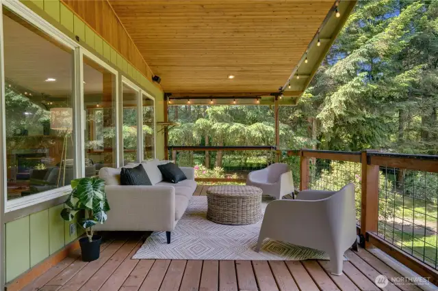 Cozy and covered outdoor living space—string lights, forest views, and the perfect setup for enjoying the outdoors year-round.