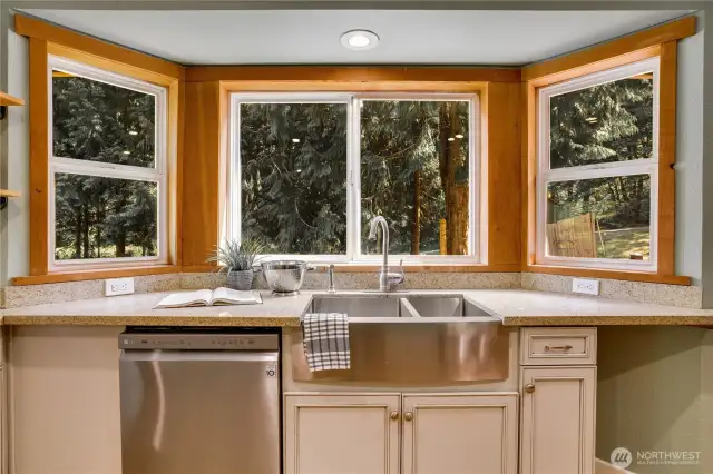 Enjoy ample counter space, stainless appliances, and a farmhouse sink overlooking lush greenery.