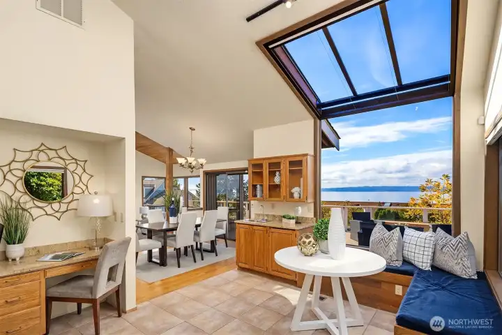 The everyday dining area features built-in banquette seating beneath a skylight and between two large picture windows that beautifully capture the views. A nearby wet bar and built-in desk add function and convenience.