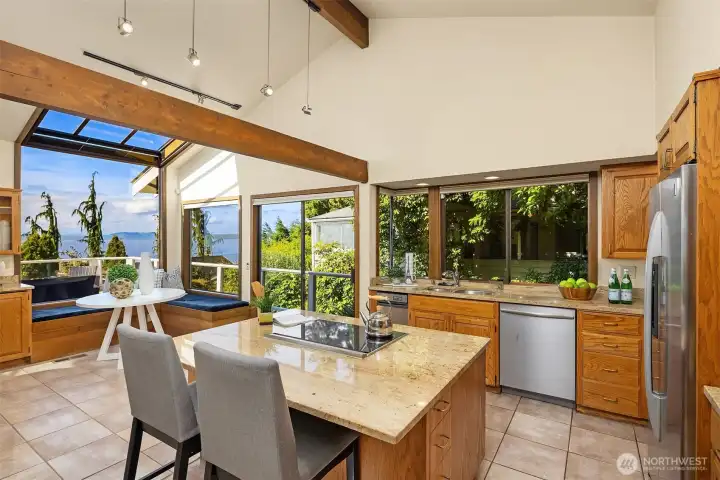 The spacious kitchen features vaulted ceilings, a large island with seating, and an open layout designed for both cooking and gathering.