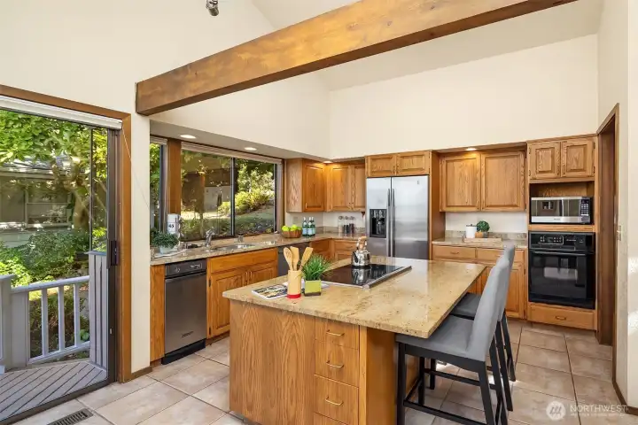 Another view of the kitchen highlights slab granite counters, stainless steel appliances, and a walk-in pantry (not shown, to the right). A convenient slider opens to the view deck for effortless indoor-outdoor living.