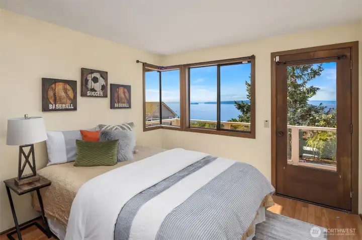 The second main-level bedroom also features laminate flooring, views, and access to the shared private deck.