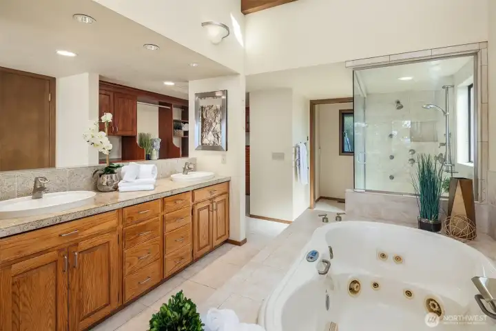 The five-piece bath features dual sinks, a jetted tub, a steam shower with dual showerheads and body sprays, a private toilet room, and a large, professionally outfitted walk-in closet.