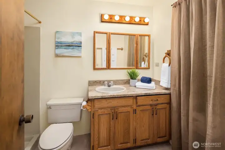 The lower-level three-quarter bath features slab granite counters. Behind the curtain is a space originally planned for a sauna, now used for storage.