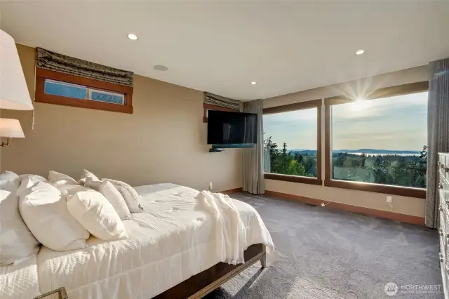 Wake up to breathtaking views from the serene primary bedroom, where oversized windows perfectly capture the morning sun and surrounding beauty.