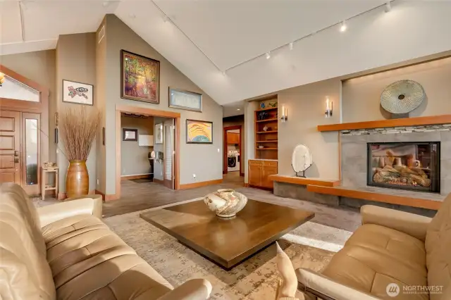 The vaulted ceilings, custom wood accents, and modern fireplace create a warm and inviting centerpiece for the home