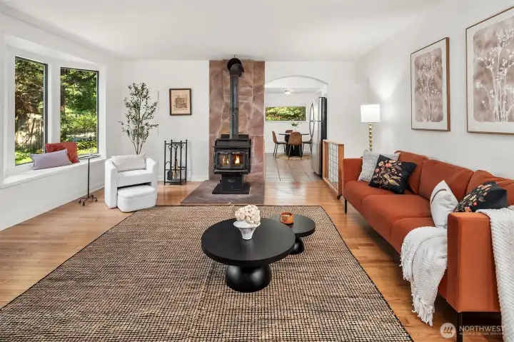 Looking through the living room with wood stove, bay window seat and doorway into kitchen. Great space for game nights.