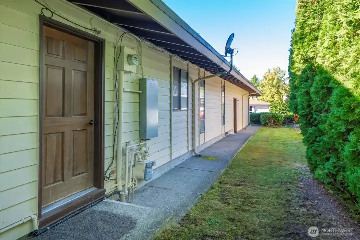 The closest door is to the utility room and the garage's door is further down along the walkway.