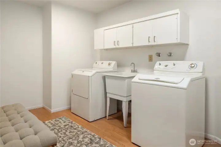 The main floor laundry room easily handles a full size washer and dryer with a laundry sink in between. The massive garage is through the door to the left (unseen) for easy off-loading of groceries.
