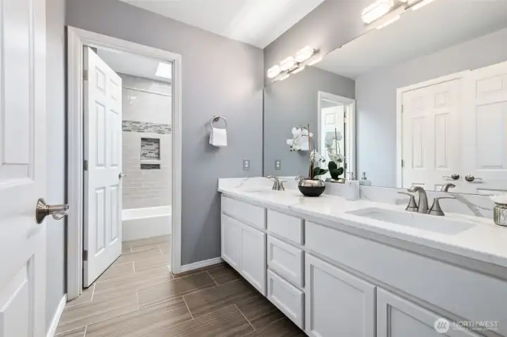 Amazing remodeled hall bath, with quartz countertop, tile flooring, new light fixtures, and new tile in the tub/shower/toilet room.
