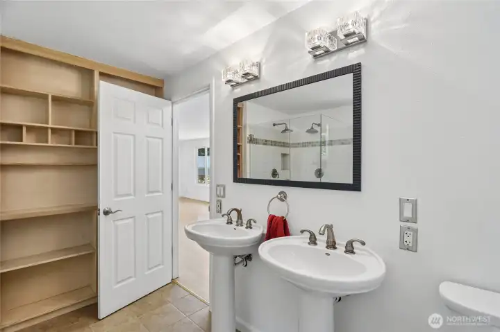 Adjoining bath with dual pedestal sinks.
