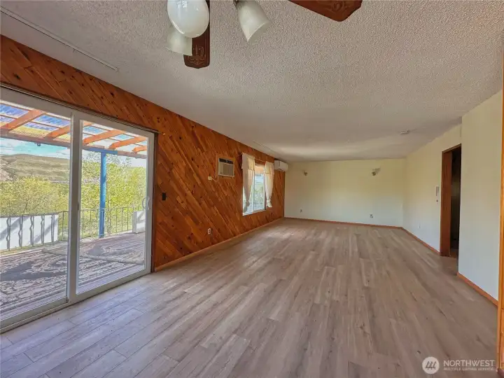 Expansive living room with dining area and sliding doors leading to a covered deck, ideal for seamless indoor-outdoor enjoyment