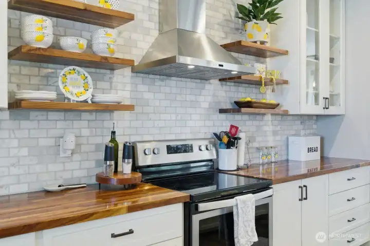 Full tiled wall and lighted stainless vent hood.