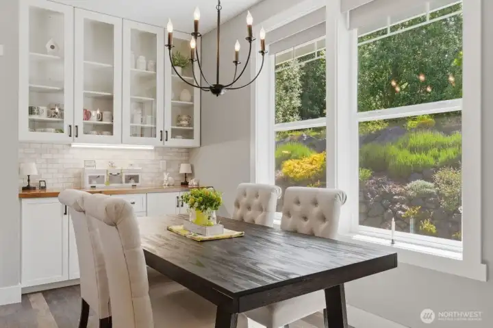 A lighted sideboard and cupboard along with large window make the dining area an inviting space to linger.