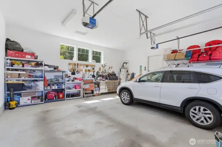 Large fully finished and insulated double garage with high ceilings and room for tools and workbench.