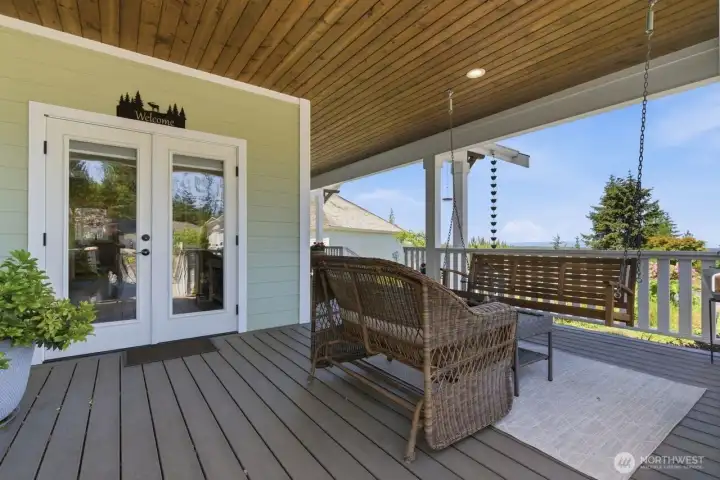 Outdoor furniture, a swing and French doors to the nearby den make the covered front porch for a space to relax and enjoy the setting.