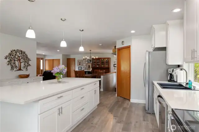The expansive island can seat at least 6 people. The corner door is the walk-in pantry with wonderful storage options