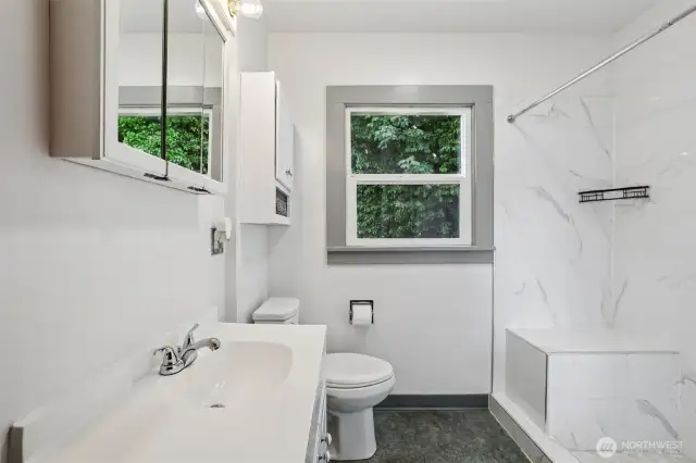 MAIN floor 3/4 Bathroom with updated tiled shower, updated tiling, window to the rear yard.
