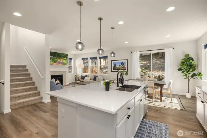 The main level is flooded with light, featuring neutral paint, beautiful laminate wood flooring, quartz counters, and spacious open-floorplan living.