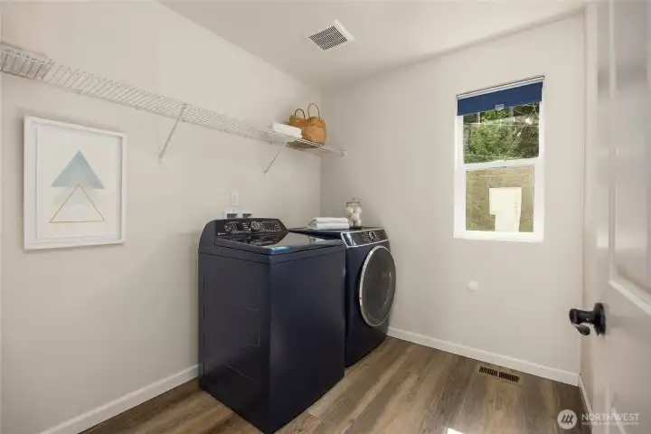 Upper level over-sized laundry room with laminate wood flooring keeps most of the laundry on the level that it is needed. Plenty of space here.