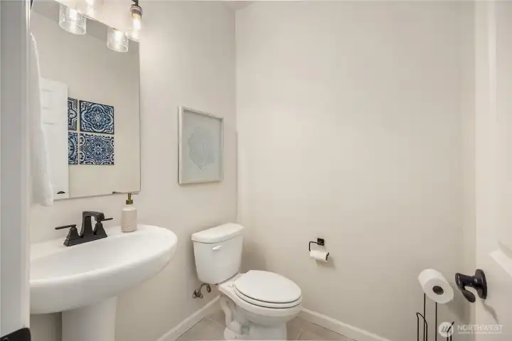 Lower level half bath features ceramic tile and black fixtures.