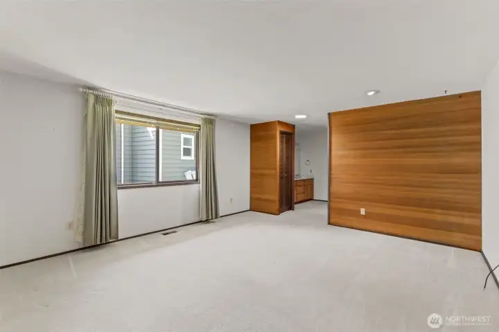 Primary bedroom featuring wood accent walls and direct access to the primary bathroom.