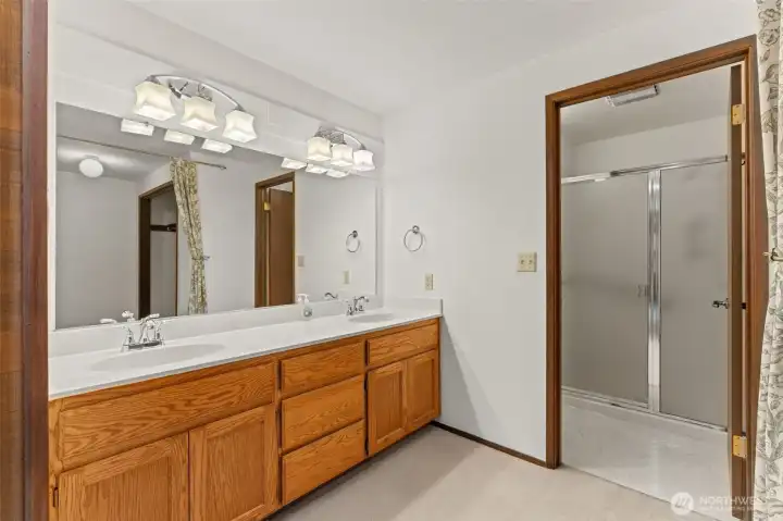 Primary bathroom featuring dual vanity sinks, with the shower and commode partitioned in a private enclosure.
