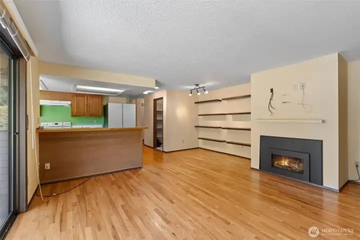 Open-concept family room featuring a seamless transition to the kitchen, convenient pantry access, a cozy fireplace, and built-in decorative shelving ready for your personal stylistic touch.