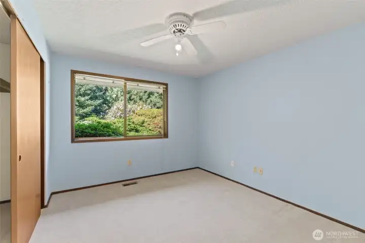 Second bedroom, featuring ample natural light and a view of the landscaped backyard.