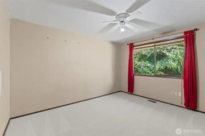 Third bedroom featuring ample natural light and a scenic view of the landscaped backyard.