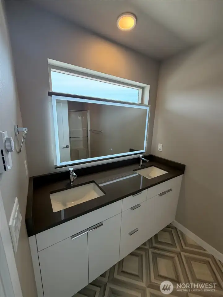 Subject property. Primary ensuite with double sinks and lit mirror