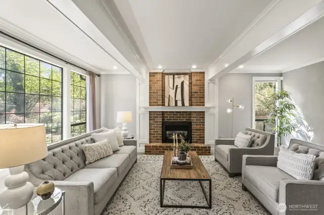 The formal living room boasts white painted beamed ceiling, crown molding and brick surround fireplace.