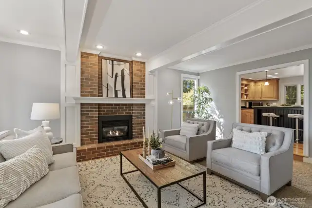 The formal living room boasts white painted beamed ceiling, crown molding and brick surround fireplace.