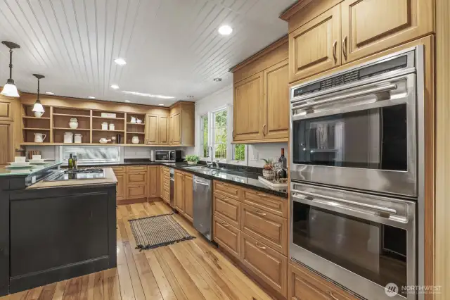 The kitchen boasts custom cabinetry, butcher block island with a Wolf gas and electric range, breakfast bar seating, stainless steel appliances including Wolf double ovens.