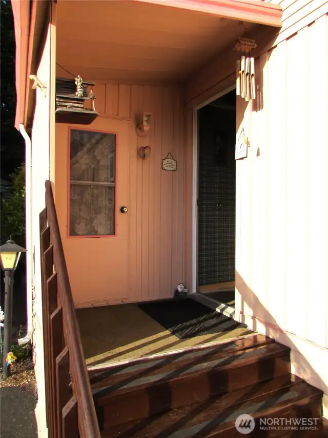 COVERED BACK DOOR ENTRY, OTHER DOOR IS ACCESS TO CLOTHES DRYER AND STORAGE ARE W/ SHELFS.