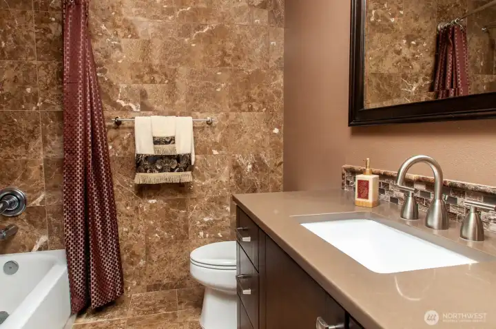 Second full bath is across the hall from the home office/bedroom and also features marble tile floor and walls.