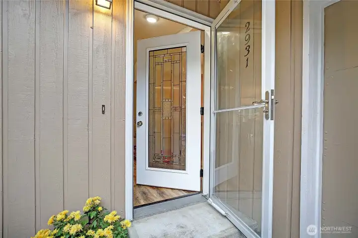 Beveled glass front entry with storm door.
