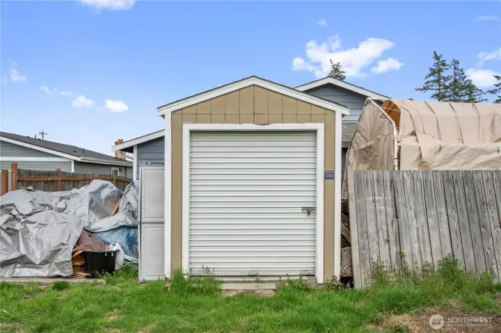 Storage shed, on a cement pad, with rollup door.