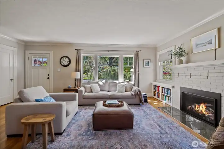 Main living area as you enter the home is light filled with a gas fireplace for a focal point flanked by built ins.  Front entry door is to rear left in photo.  Oak hardwoods & crown molding contrast soft interior paint color.