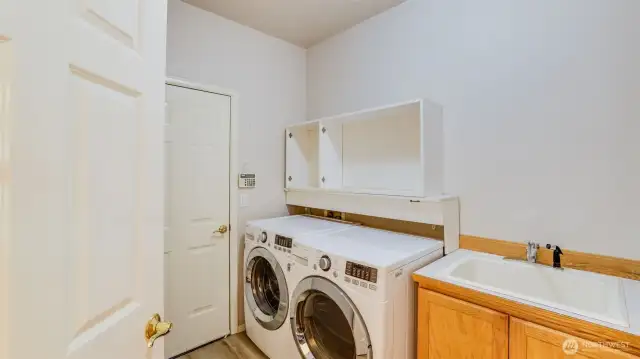 This laundry room includes a washer and dryer, along with a built-in sink for added ease and convenience