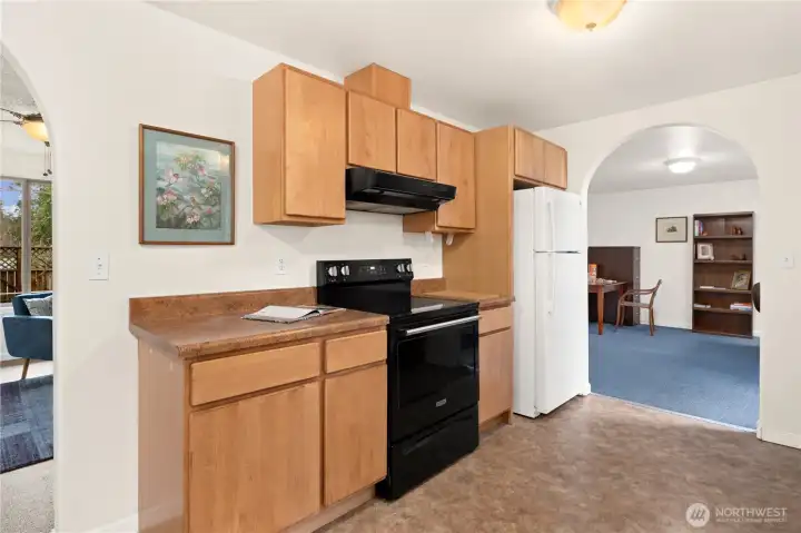 Kitchen with a view to the living room on left and another arched opening to the family room or den.