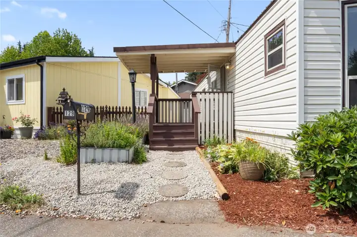 Covered deck greets you into the home. New flowers and garden area.