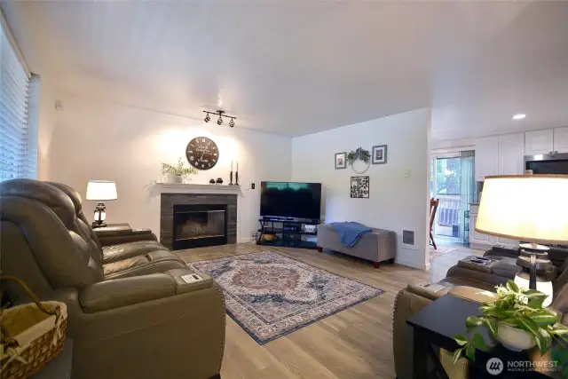 Living room with cozy wood fire place, huge windows looking out to front yard.