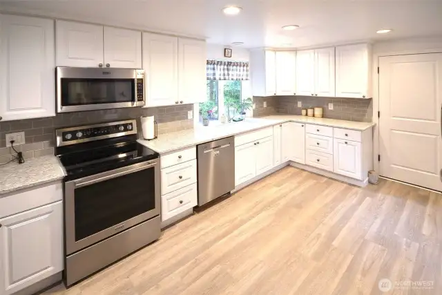 Beautiful kitchen has a roll away island that comes with the home. New kitchen cabinets, soft close, pull outs, beautiful quartz countertops, newer appliances, Tile back splash, new LVP flooring.