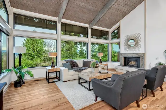 The living room is a showstopper, featuring soaring vaulted ceilings with rich wood paneling that adds warmth and character. Transom windows flood the space with natural light, creating a bright and airy ambiance.