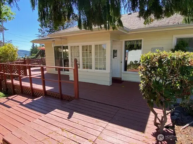 Front door, enclosed vestibule, and deck from driveway.