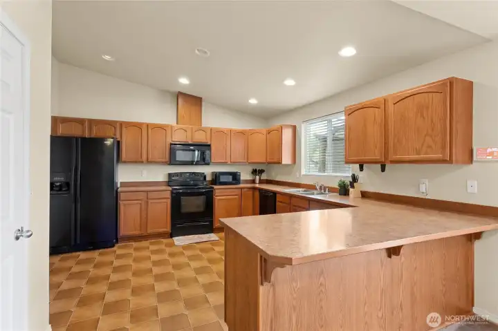 Kitchen with electric stove. Area for bar stools.