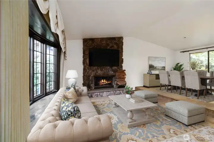 <Virtually Staged> Spacious living room featuring a dramatic floor-to-ceiling stone fireplace and abundant natural light