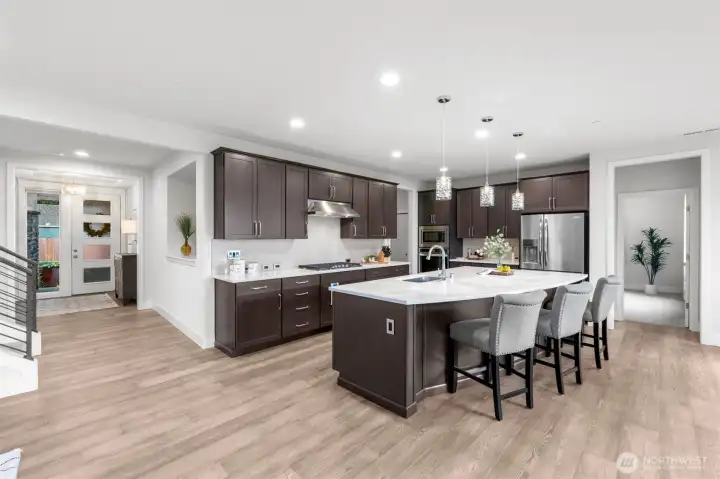 Breathtaking kitchen features large quartz island with prep sink, stainless steel appliances, gas range and plenty of storage.